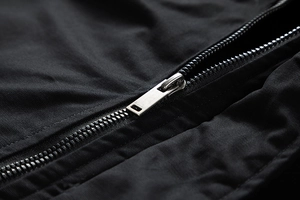 Detail of silver metal zipper on a black winter jacket with smooth textured fabric