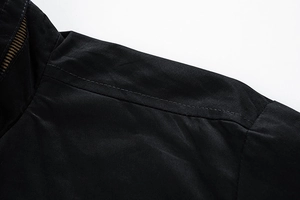 Detail of black jacket shoulder with precise double stitching and striped collar tape