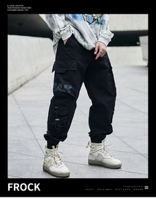 Detail of black multi-pocket cargo pants featuring RAD letter print and tapered cuffs