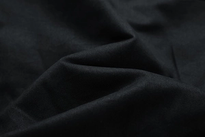 Close-up detail of high-quality black washed cotton fabric with fine twill weave texture