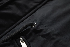 Detail of black washed jacket featuring metal eyelets, woven drawstring, and a smooth zipper
