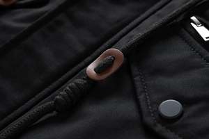 Detail of black washed jacket featuring leather drawstring toggle and matte metal snap button