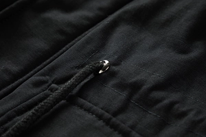 Detailaufnahme der schwarzen Herren-Winterjacke mit Metallösen und strapazierfähigen Kordelzügen