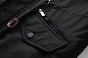 Detail of a black twill jacket featuring a metal snap pocket and high-quality zipper