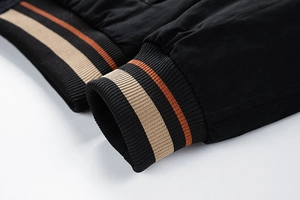 Detail of men's bomber jacket showing striped knit ribbed cuffs and hem in black fabric