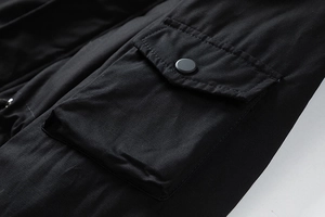 Detailed view of black cargo jacket flap pocket with matte metal snap button and stitching