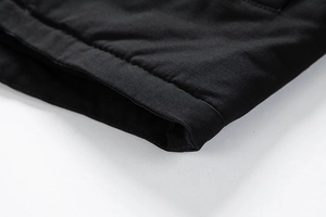 Detail-Makroaufnahme der Doppelnaht am Ärmelbündchen der schwarzen Winterjacke aus Baumwolle