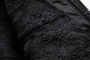 Nahaufnahme des dicken schwarzen Fleecefutters und der Nähte dieser warmen Winterjacke
