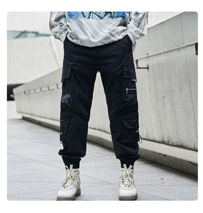 Detailed view of black multi-pocket techwear cargo pants with tactical zippers and ribbed cuffs