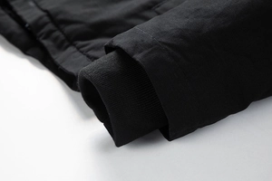 Nahaufnahme der winddichten Rippstrickbündchen an der langen schwarzen Winterjacke
