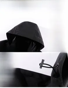 Detail of adjustable windproof hood with drawstring and plastic toggles on black jacket
