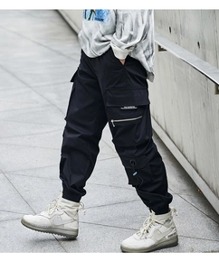 Detailed view of multi-pocket techwear cargo pants with side zippers and straps