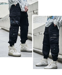 Detail view of black cargo pants featuring multiple pockets and BAR ORIGINAL DESIGN print