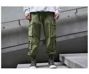 Detail view of military green cargo pants featuring side flap pockets and white logo