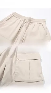 Detailed view of elastic drawstring waist and large 3D cargo side pockets on beige shorts