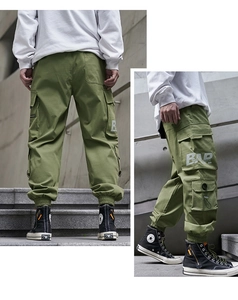 Detail of military green cargo pants featuring side flap pockets and printed typography