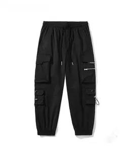 Detail view of black multi-pocket cargo pants with white lettering and elastic cuffs