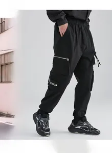 Detail of black techwear cargo pants featuring silver zippers and side strap elements