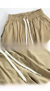 Detail of khaki cargo shorts showing elastic waistband with white drawstring and twill fabric