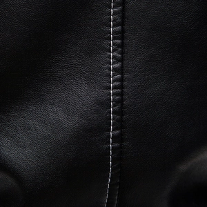 Detailed close-up of premium black PU leather with contrast white stitching and grain texture