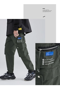 Detail of dark green cargo pants featuring functional pockets and white graphic prints