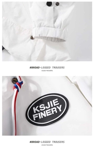 Detailed view of the KSJIE FINERY brand patch and tricolor drawstring on white casual trousers