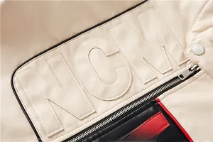 Detail of beige faux leather jacket featuring NGM letter embroidery and red-black contrast