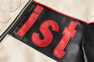Detail of color-block biker jacket featuring red ist embroidery and leather texture