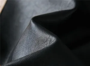 Macro shot of high-quality black faux leather texture with soft grain and subtle gloss