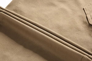 Makro-Detail von khakifarbenem Baumwolltwill mit fester Textur und Doppelnähten an der Hose