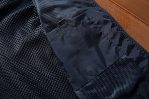 Macro detail of the breathable mesh lining and inner pocket on a dark blue outdoor vest