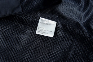 Macro detail of breathable mesh fabric and product care label on black fishing vest