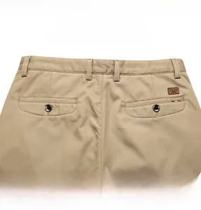 Close-up of khaki casual pants back pocket with leather brand label and stitching details