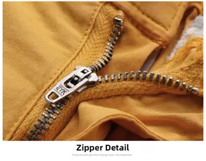 Detailed close-up of the metal ZYK zipper on yellow cotton cargo shorts fabric