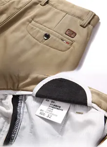 Detail of khaki trousers featuring back pocket leather patch and fabric composition label
