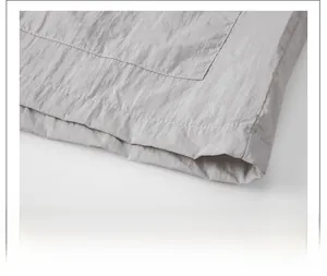 Detailed macro view of smooth hem stitching and thin nylon fabric texture on grey jacket
