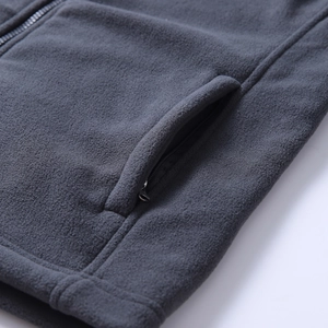 Detailed macro view of dark grey fleece jacket featuring high-quality zipper and soft texture