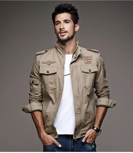 Detail of khaki military jacket featuring functional flap pockets and vintage embroidery patches