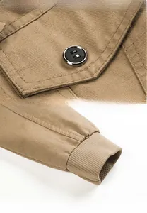 Detail of khaki men's jacket showing shoulder stitching, black buttons, and ribbed cuffs