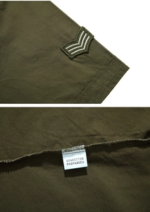 Detail of military green shirt showing V-shaped embroidered patch and fabric care label