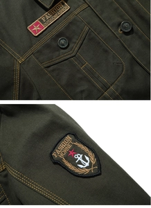 Détail de la veste en toile vert olive avec broderie de marque et boutons métalliques