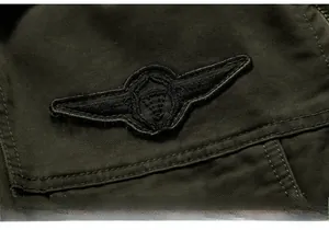 Macro detail of military-style cotton jacket featuring a black embroidered wing patch