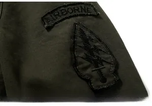 Detailed view of AIRBORNE embroidered patches on military green cotton utility jacket