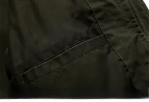 Macro detail of the durable cotton twill fabric and secure inner zipper pocket on the jacket