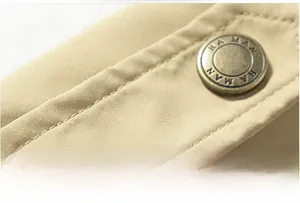 Close-up of khaki military jacket shoulder featuring reinforced stitching and metal button