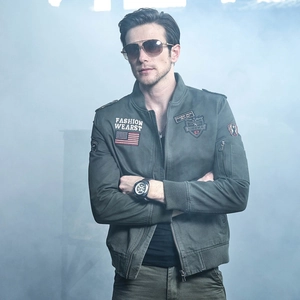Detail of military green bomber jacket featuring tactical embroidered patches and rib cuffs