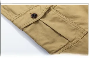 Macro detail of khaki cargo shorts showing button closure and reinforced flap pocket