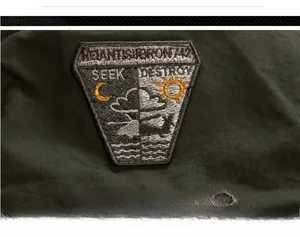 Detail of military green canvas jacket with helicopter shield embroidery and text