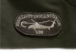 Macro detail of military-style helicopter embroidery patch on olive green twill jacket