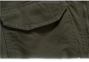 Detailed macro view of olive green military jacket with reinforced flap pockets and stitching